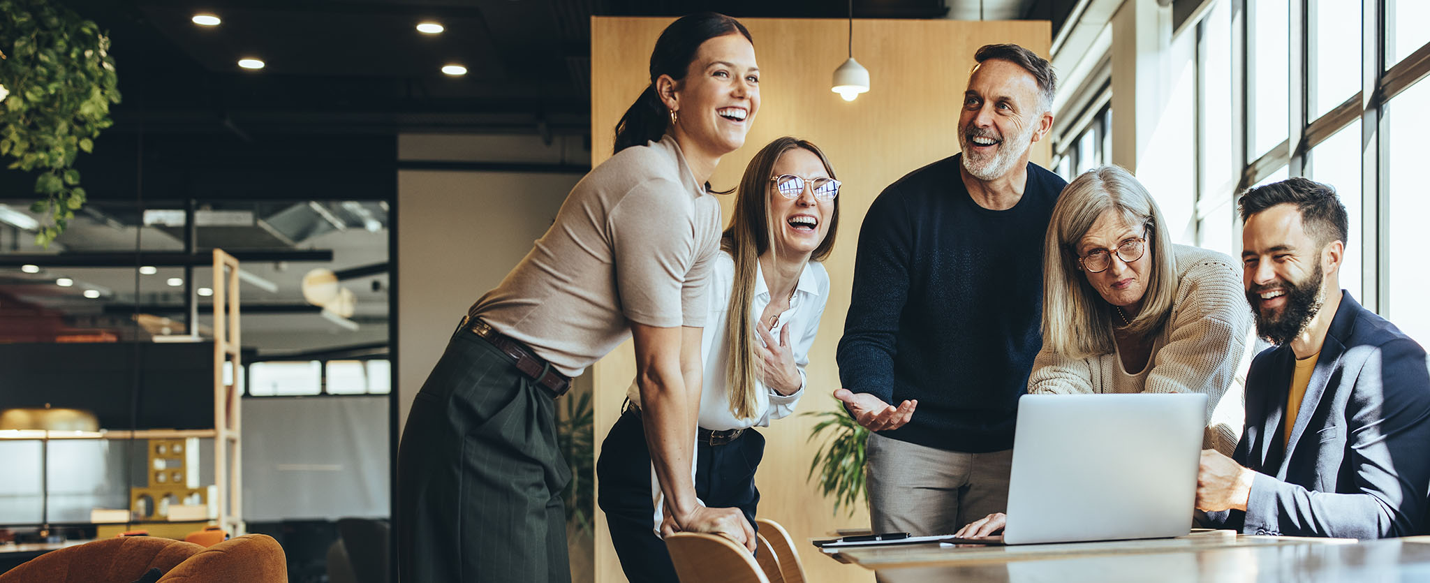Happy team of business professionals collaborating around a laptop